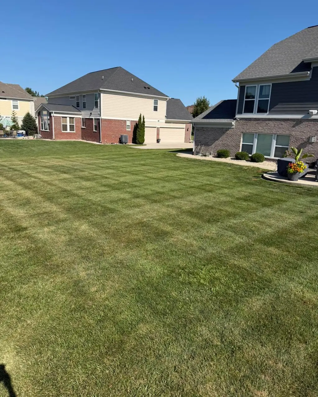 The side lawn of a newer two storey home cut in even stripes running toward the driveway